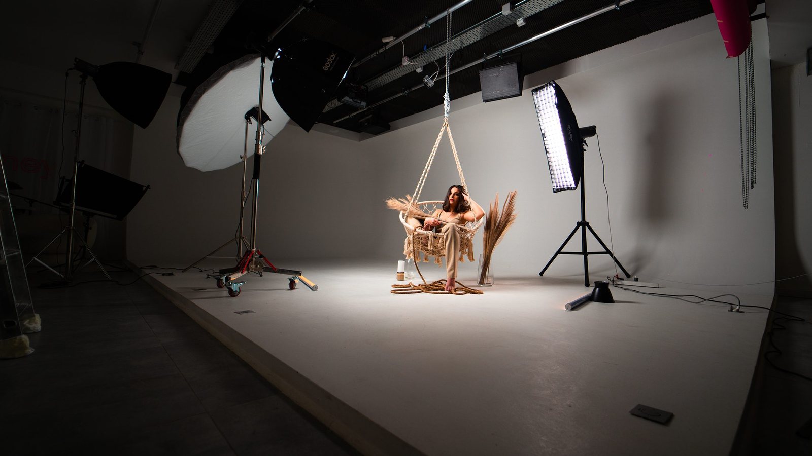 Le cyclorama du Studio Urban éclairé pour un shooting : une modèle assise dans un fauteuil suspendu, softboxes de part et d'autre.